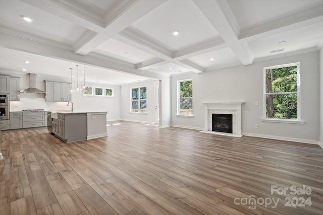 unfurnished living room featuring light hardwood / wood-style floors, beamed ceiling, a wealth of natural light, and coffered ceiling