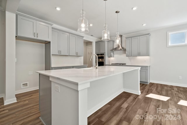 kitchen with hanging light fixtures, light stone countertops, a large island with sink, and tasteful backsplash