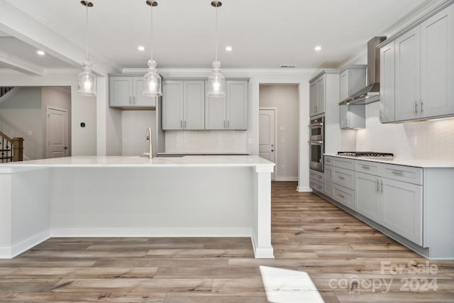 kitchen with wall chimney exhaust hood, gray cabinetry, pendant lighting, and tasteful backsplash