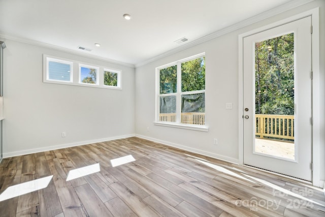 spare room with a wealth of natural light, crown molding, and light hardwood / wood-style floors