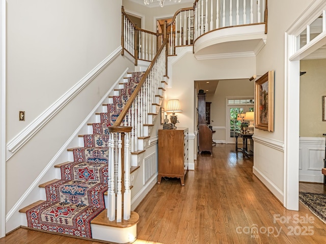 stairs with a high ceiling, hardwood / wood-style floors, and crown molding