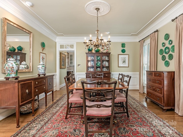 dining space with wood-type flooring, crown molding, and a chandelier