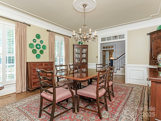 dining room featuring hardwood / wood-style floors, crown molding, and an inviting chandelier