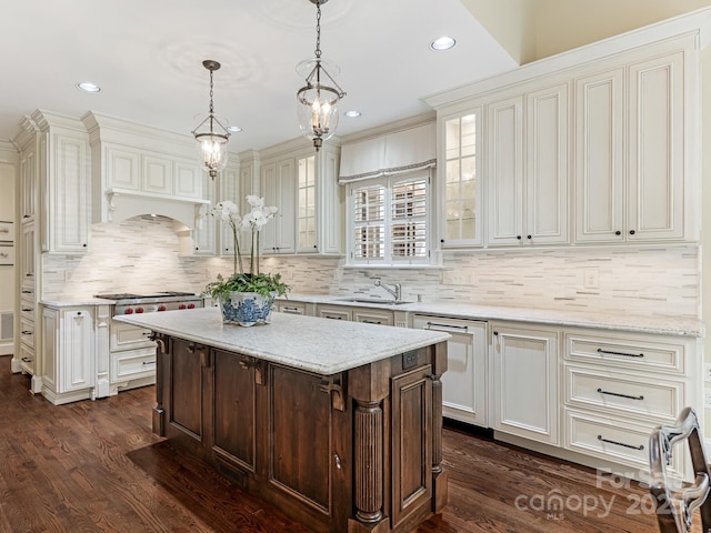 kitchen featuring dark wood-type flooring, a kitchen island, hanging light fixtures, and light stone countertops