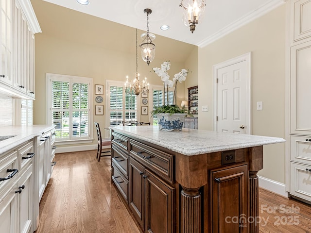 kitchen featuring ornamental molding, white cabinets, a chandelier, light hardwood / wood-style flooring, and a center island