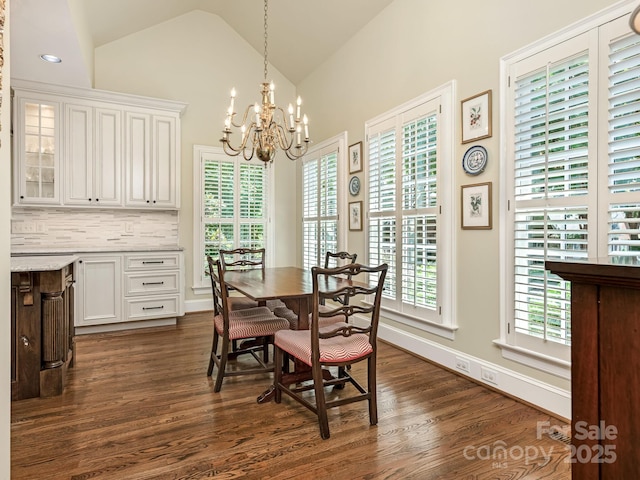 dining room with high vaulted ceiling, dark hardwood / wood-style floors, a wealth of natural light, and a chandelier