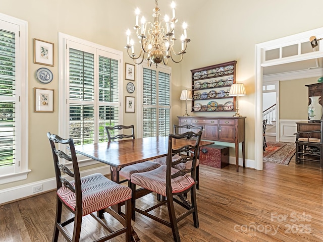 dining room with dark wood-type flooring, plenty of natural light, and a notable chandelier