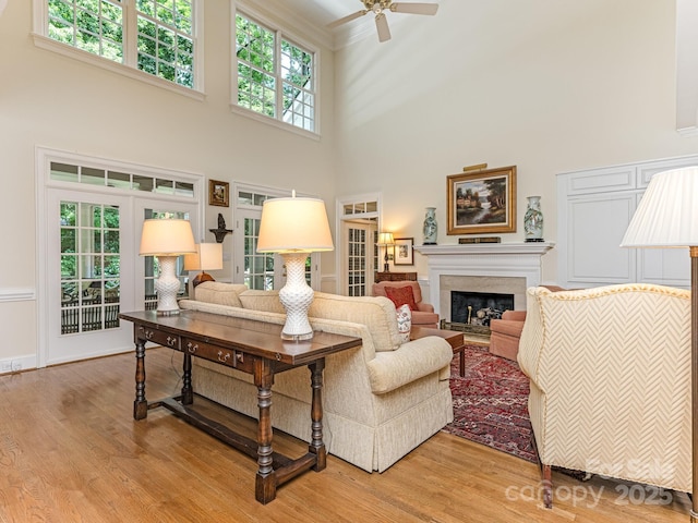 living room featuring ceiling fan, a wealth of natural light, wood-type flooring, and a high ceiling