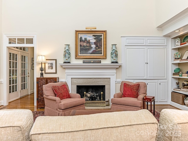 living room featuring built in features, a fireplace, and light hardwood / wood-style flooring