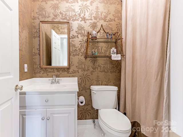 bathroom with toilet, vanity, and tile patterned flooring