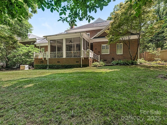 rear view of property with ceiling fan, a sunroom, and a lawn