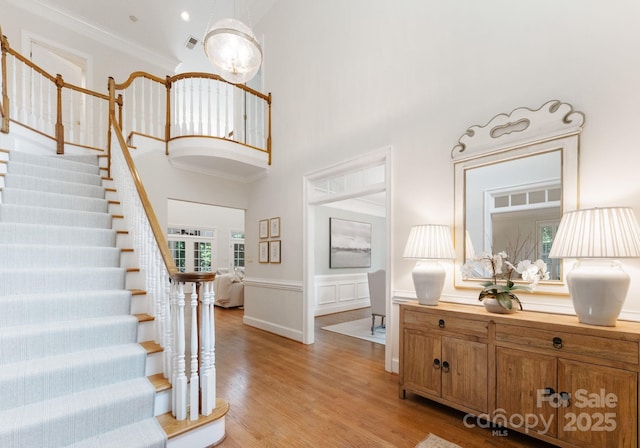 4301 Fairview Oaks Dr, Charlotte, NC 28211 - foyer entrance featuring stairs, light wood-style floors, a wainscoted wall, a high ceiling, and crown molding