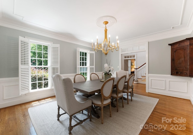 4301 Fairview Oaks Dr, Charlotte, NC 28211 - dining room with a chandelier, a wainscoted wall, crown molding, light wood-style floors, and stairs