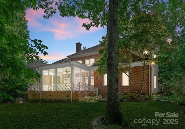 4301 Fairview Oaks Dr, Charlotte, NC 28211 - property exterior at dusk featuring crawl space, a sunroom, a yard, a chimney, and brick siding