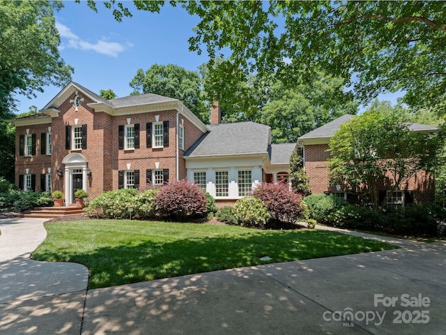 4301 Fairview Oaks Dr, Charlotte, NC 28211 - georgian-style home with brick siding, a chimney, and a front lawn