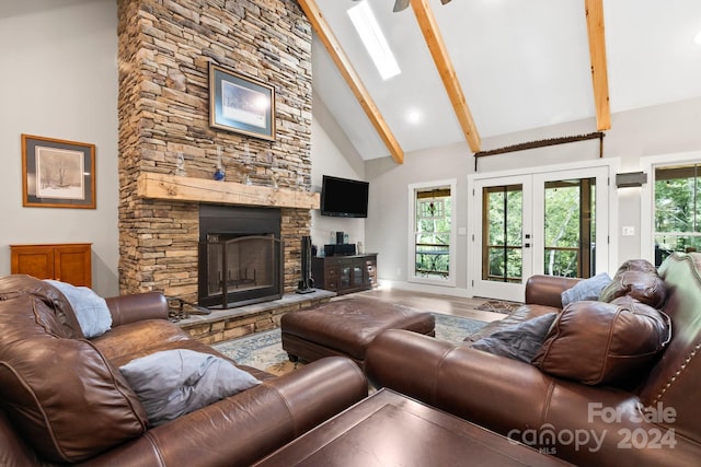 living room with high vaulted ceiling, a stone fireplace, beamed ceiling, hardwood / wood-style flooring, and a skylight