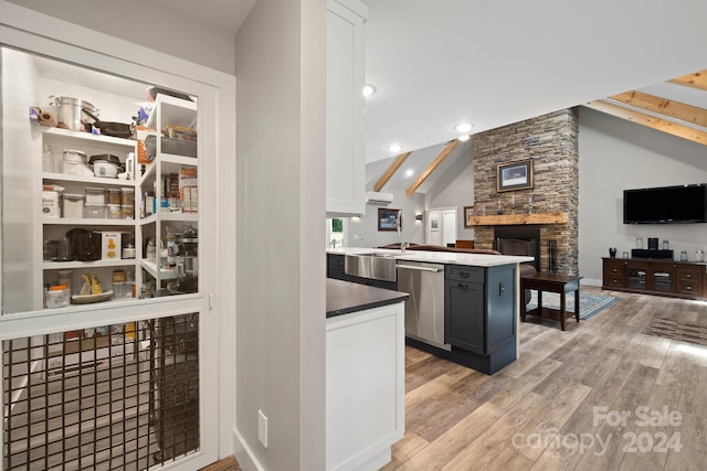 kitchen with vaulted ceiling with beams, sink, a fireplace, light hardwood / wood-style flooring, and stainless steel dishwasher