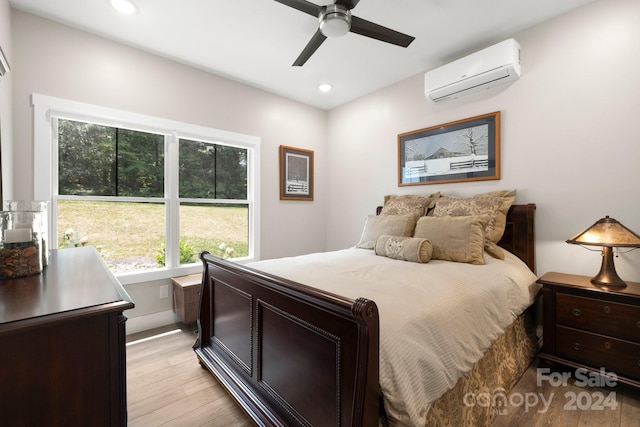 bedroom with ceiling fan, light hardwood / wood-style flooring, and a wall unit AC