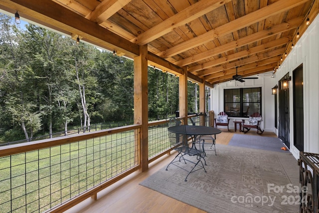 sunroom / solarium featuring ceiling fan, vaulted ceiling with beams, wooden ceiling, and a healthy amount of sunlight