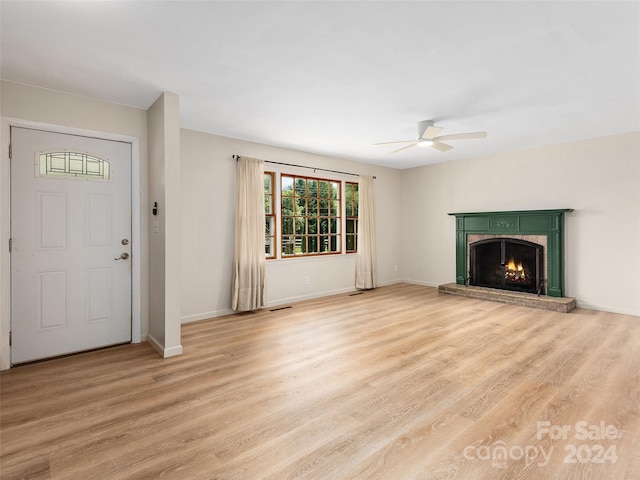 unfurnished living room featuring a brick fireplace, light wood-type flooring, and ceiling fan