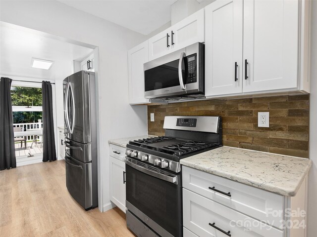 kitchen featuring decorative backsplash, appliances with stainless steel finishes, light stone countertops, white cabinets, and light hardwood / wood-style floors