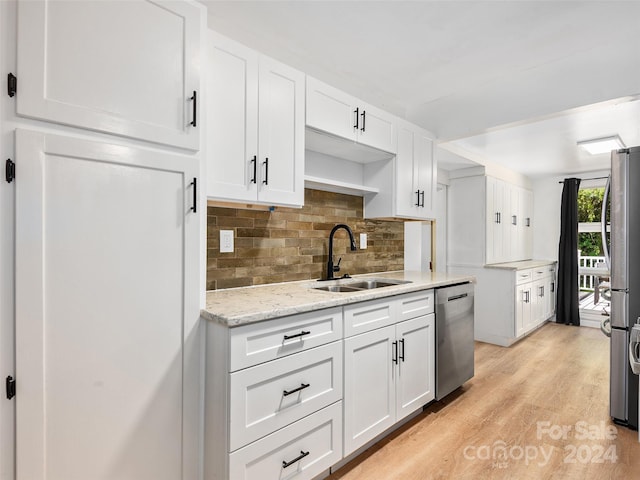 kitchen with decorative backsplash, appliances with stainless steel finishes, white cabinets, light hardwood / wood-style floors, and sink