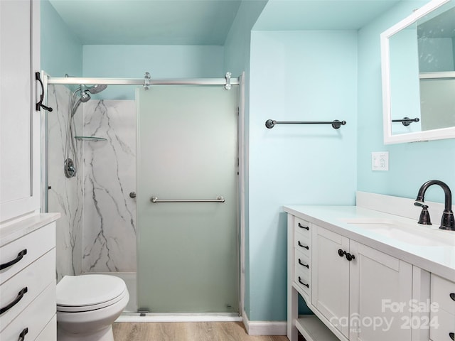 bathroom with toilet, vanity, hardwood / wood-style flooring, and an enclosed shower