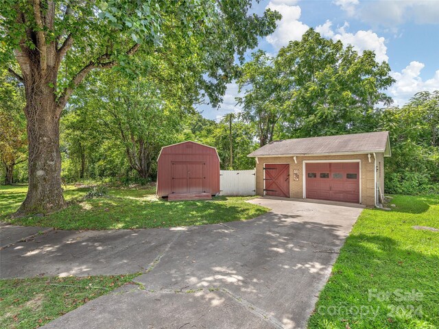 exterior space featuring a garage, a front yard, and a storage shed