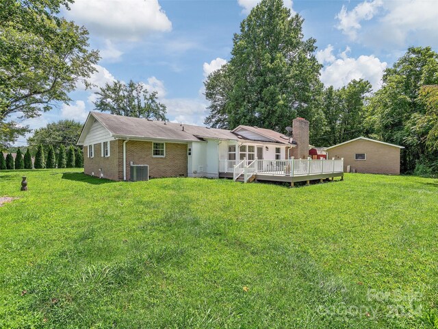 rear view of property featuring central AC, a yard, and a deck