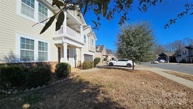 view of side of property featuring a balcony and a garage