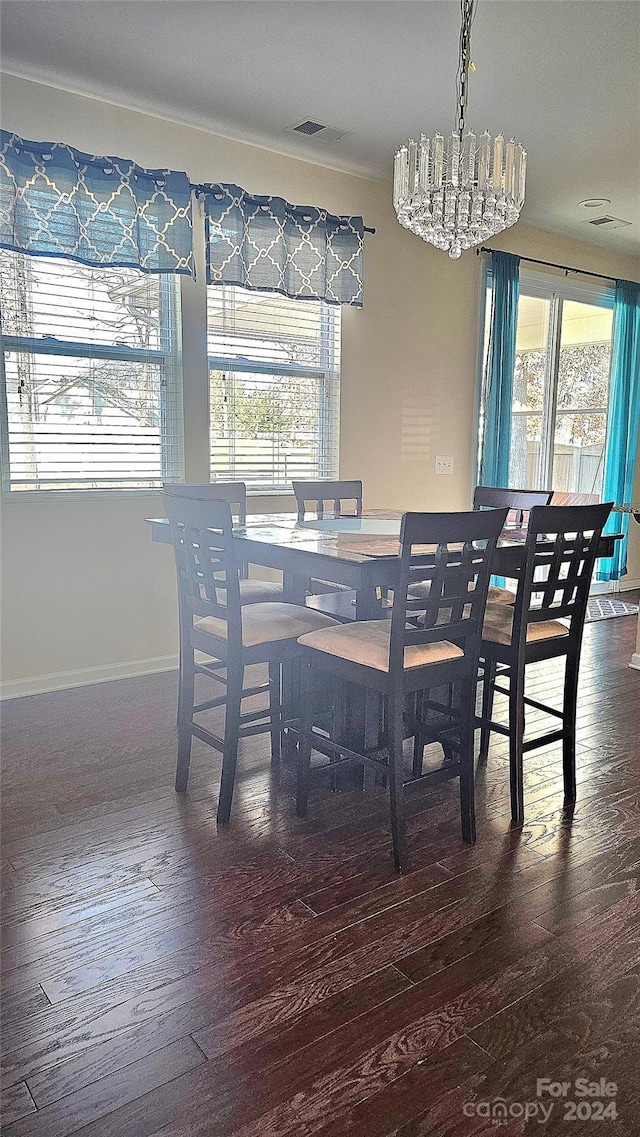 dining room with a chandelier, visible vents, baseboards, and hardwood / wood-style flooring