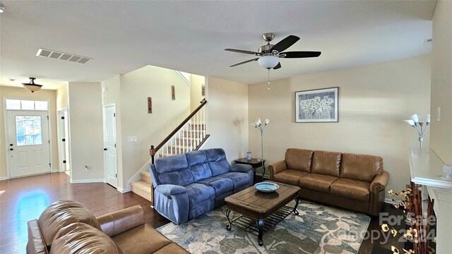 living area with stairway, a ceiling fan, wood finished floors, visible vents, and baseboards