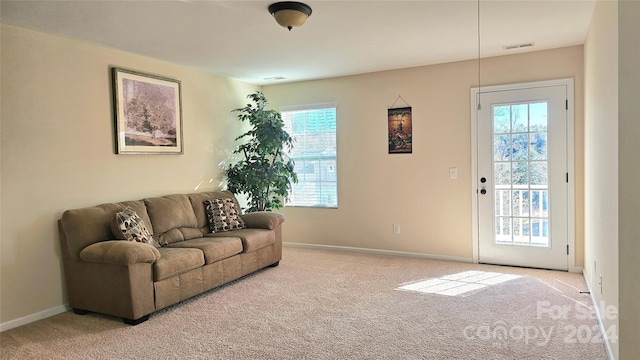 carpeted living area featuring plenty of natural light, baseboards, and visible vents