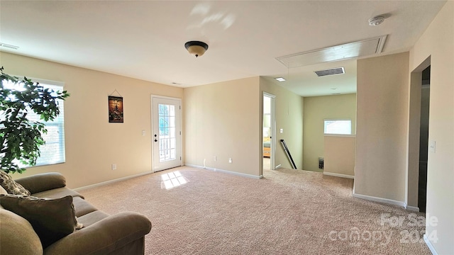 carpeted living area with visible vents, attic access, and baseboards