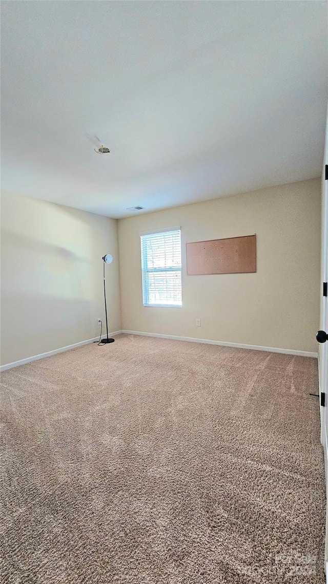 carpeted spare room featuring baseboards