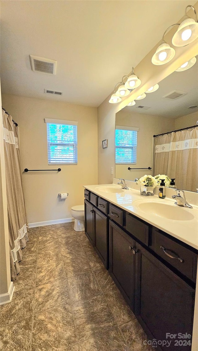 full bath featuring toilet, visible vents, a wealth of natural light, and a sink