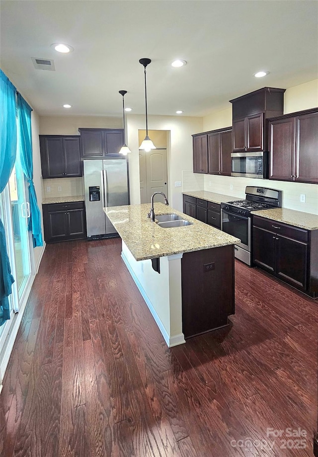 kitchen featuring light stone countertops, visible vents, dark wood finished floors, stainless steel appliances, and a sink