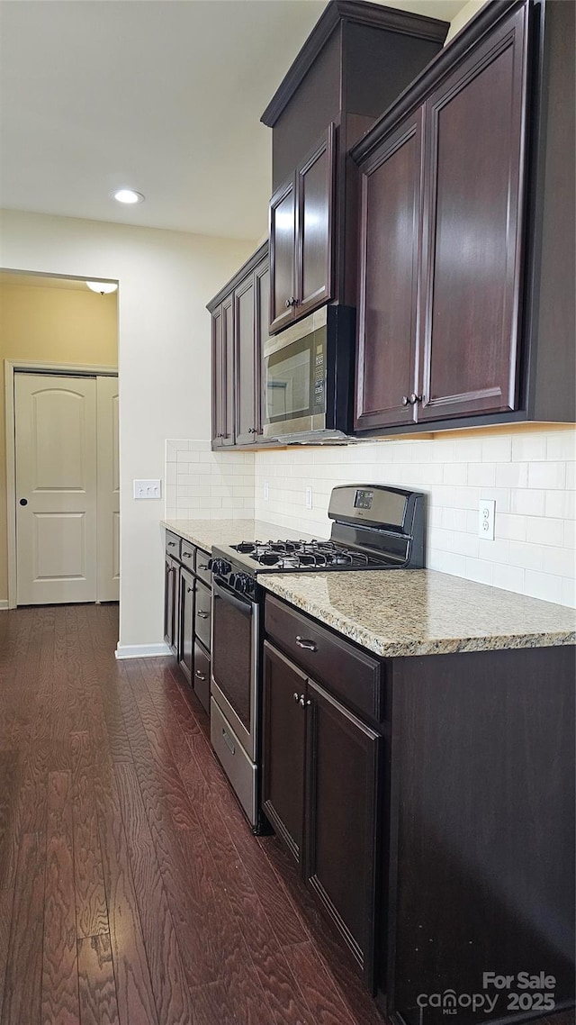 kitchen with tasteful backsplash, baseboards, dark wood-style floors, light stone countertops, and stainless steel appliances