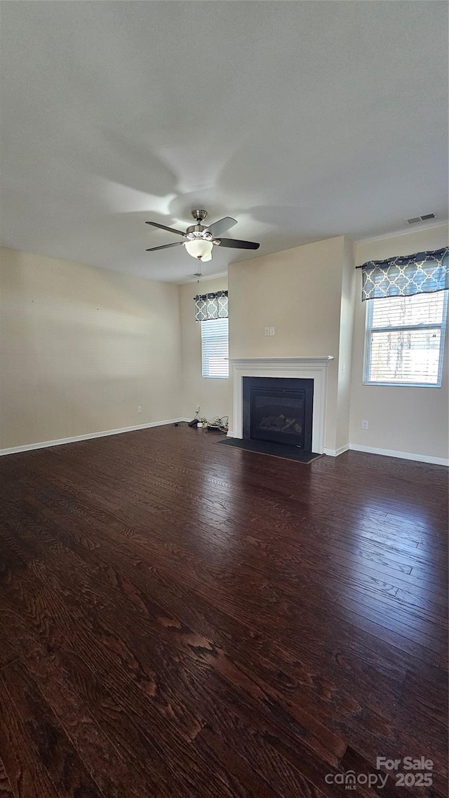 unfurnished living room featuring visible vents, wood finished floors, a fireplace with flush hearth, and a healthy amount of sunlight