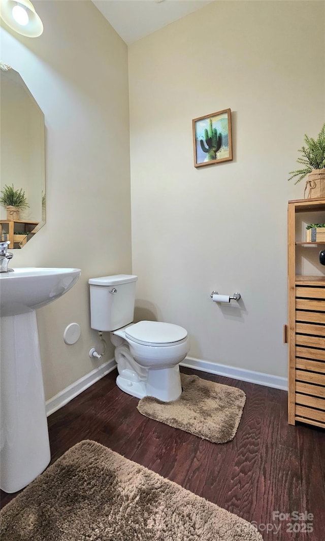 bathroom featuring toilet, wood finished floors, and baseboards