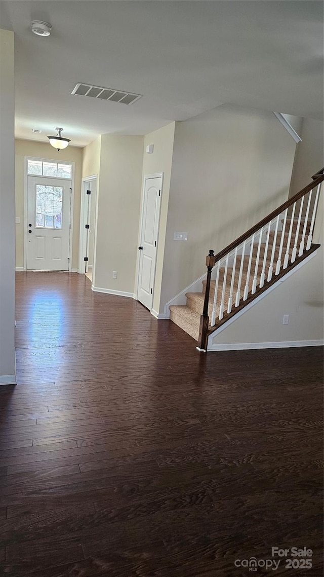 foyer entrance featuring visible vents, baseboards, wood finished floors, and stairs