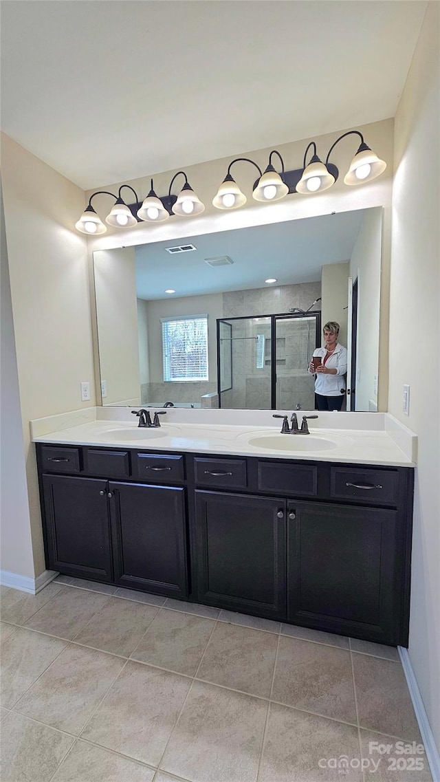 bathroom with double vanity, a sink, and a stall shower