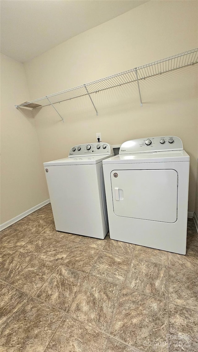 washroom featuring laundry area, separate washer and dryer, and baseboards