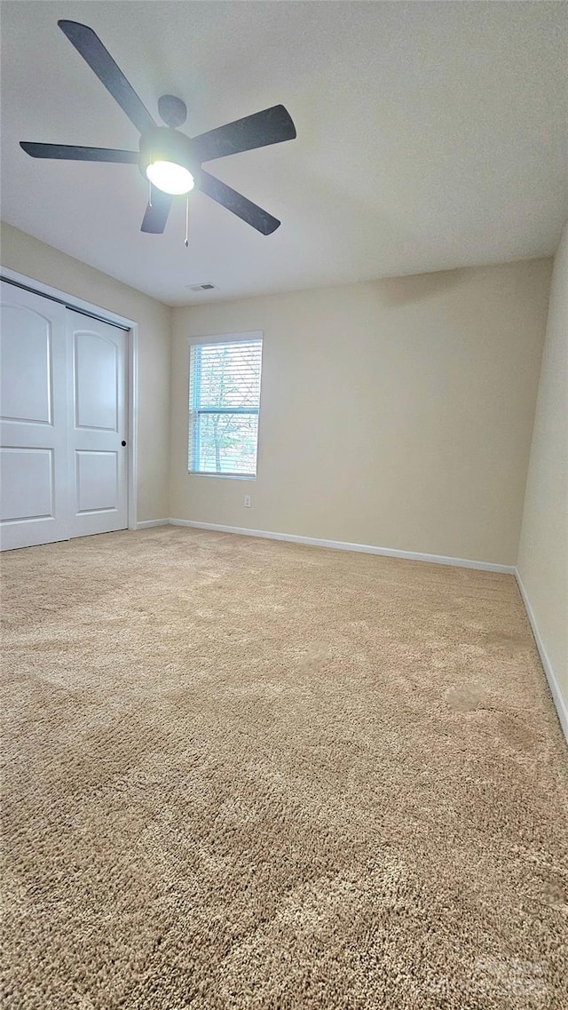 unfurnished bedroom with a closet, baseboards, carpet flooring, and ceiling fan