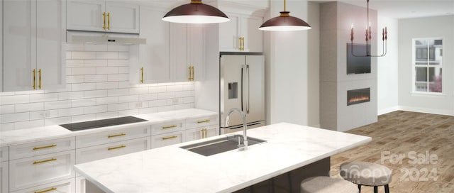 kitchen with white refrigerator with ice dispenser, decorative light fixtures, a fireplace, wood-type flooring, and tasteful backsplash