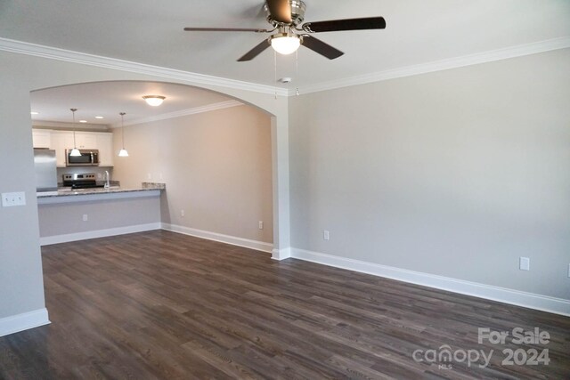 unfurnished living room featuring ceiling fan, dark wood-type flooring, and ornamental molding