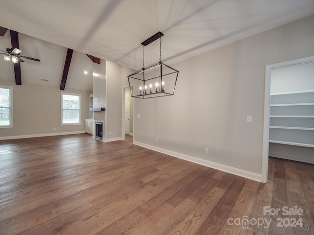 unfurnished living room with wood-type flooring, ceiling fan with notable chandelier, and lofted ceiling with beams