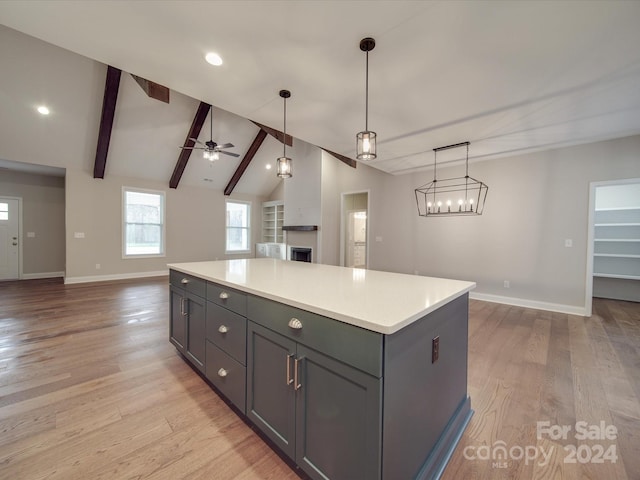 kitchen featuring beam ceiling, ceiling fan with notable chandelier, hanging light fixtures, and light hardwood / wood-style floors