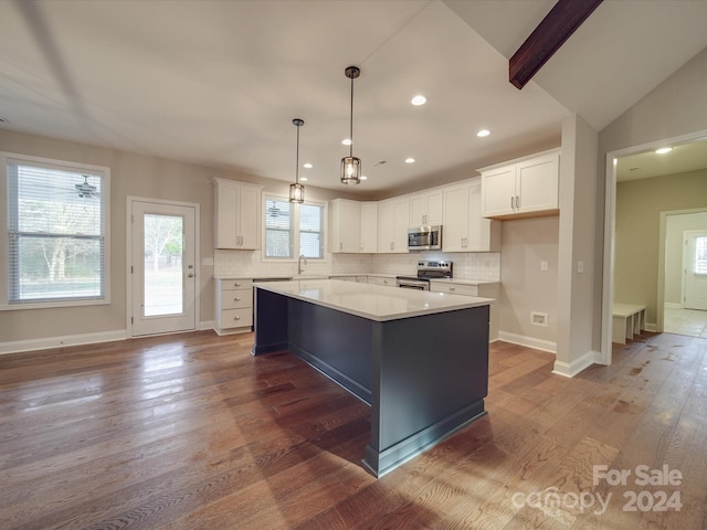 kitchen featuring stainless steel appliances, hardwood / wood-style flooring, white cabinetry, and a kitchen island