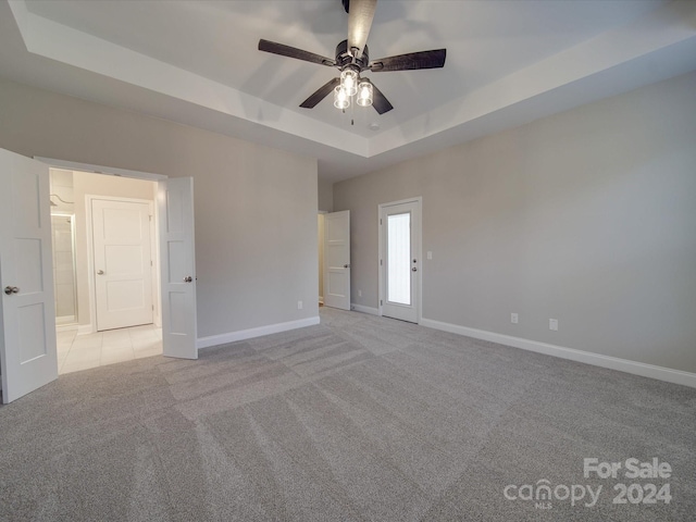 carpeted empty room featuring ceiling fan and a tray ceiling